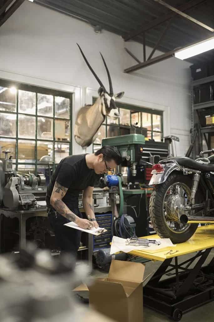 Motorcycle mechanic with clipboard checking inventory in auto repair shop