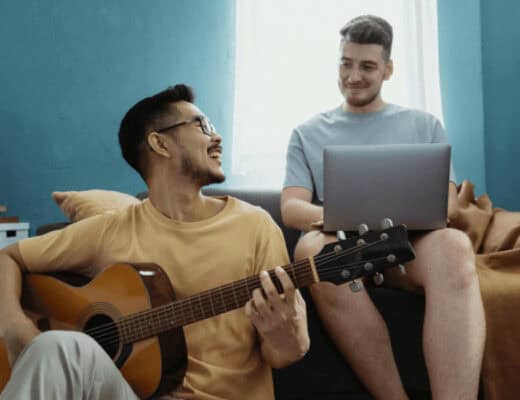 Man playing guitar on couch in shared living room