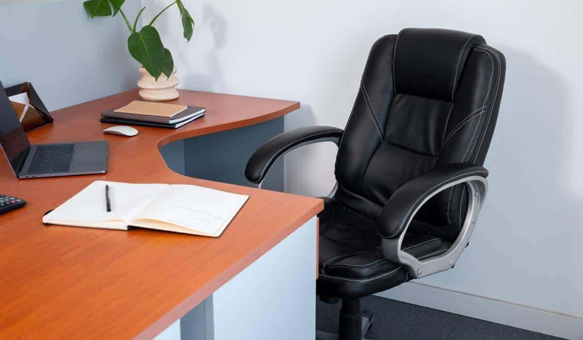 A black office chair beside a wooden desk in a home office setting