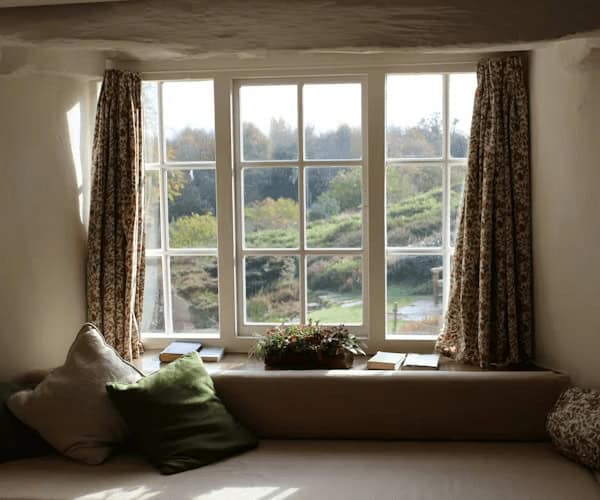 Cozy window seat with pillows and plant,