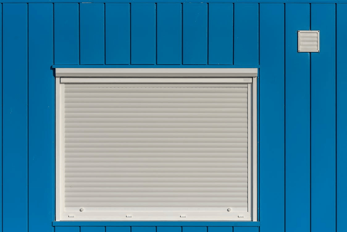 Ways to Improve Your House’s Ability to Withstand a Storm 1 Blue building with white shutter, ready for a storm