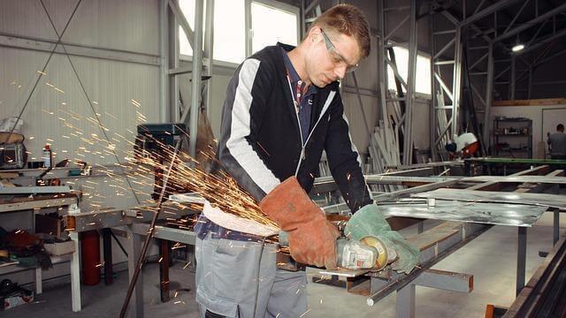 Man operating a grinder power tool to shape metal