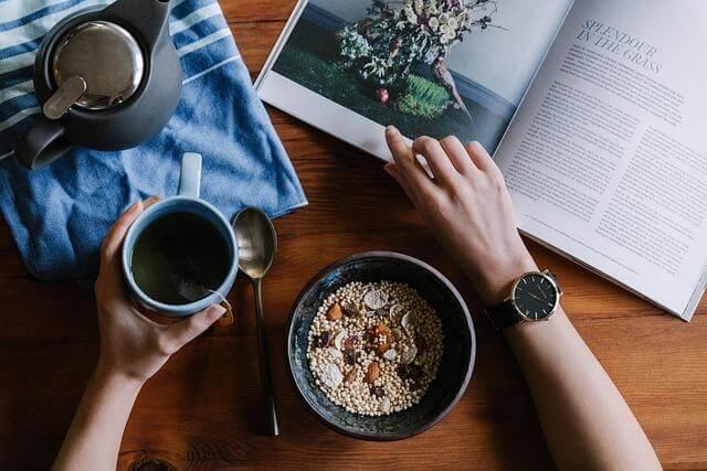 7 New Tea Traditions To Try on International Tea Day 2 Person enjoying breakfast cereal and a book at a table