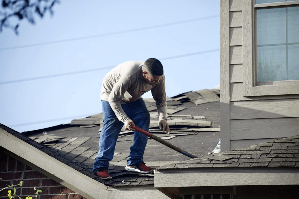 Man with hammer repairing roof to protect home