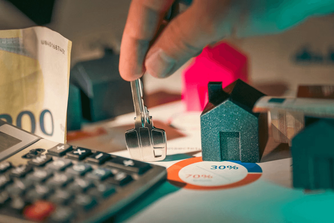 Creative Ways to Build a Down Payment for Your First Home 3 Person holding a house key next to a calculator
