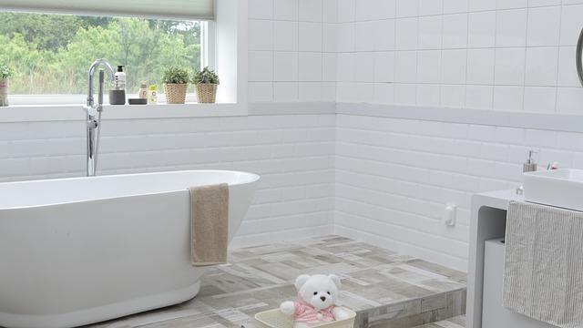 White bathroom with tub and a teddy
