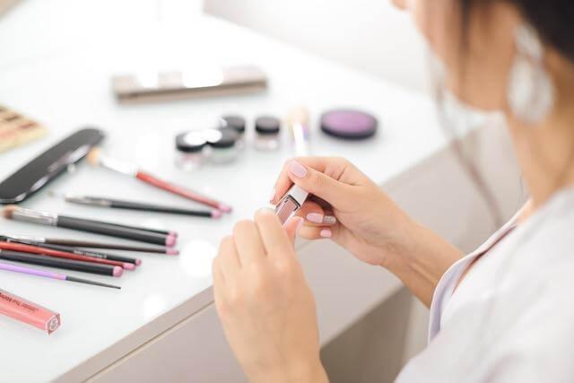Woman applying makeup at a vanity, illustrating a
