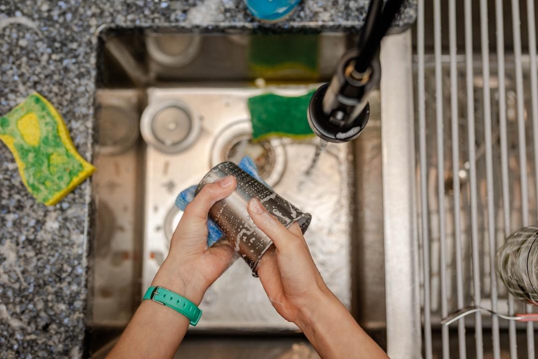 When a DIY Repair List Outgrows Your Skills and Budget 2 A person kneeling to repair a pipe under a sink using a hand wrench