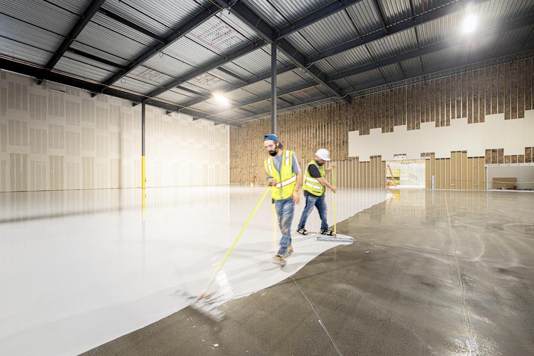 A worker applying floor coating with a roller on concrete
