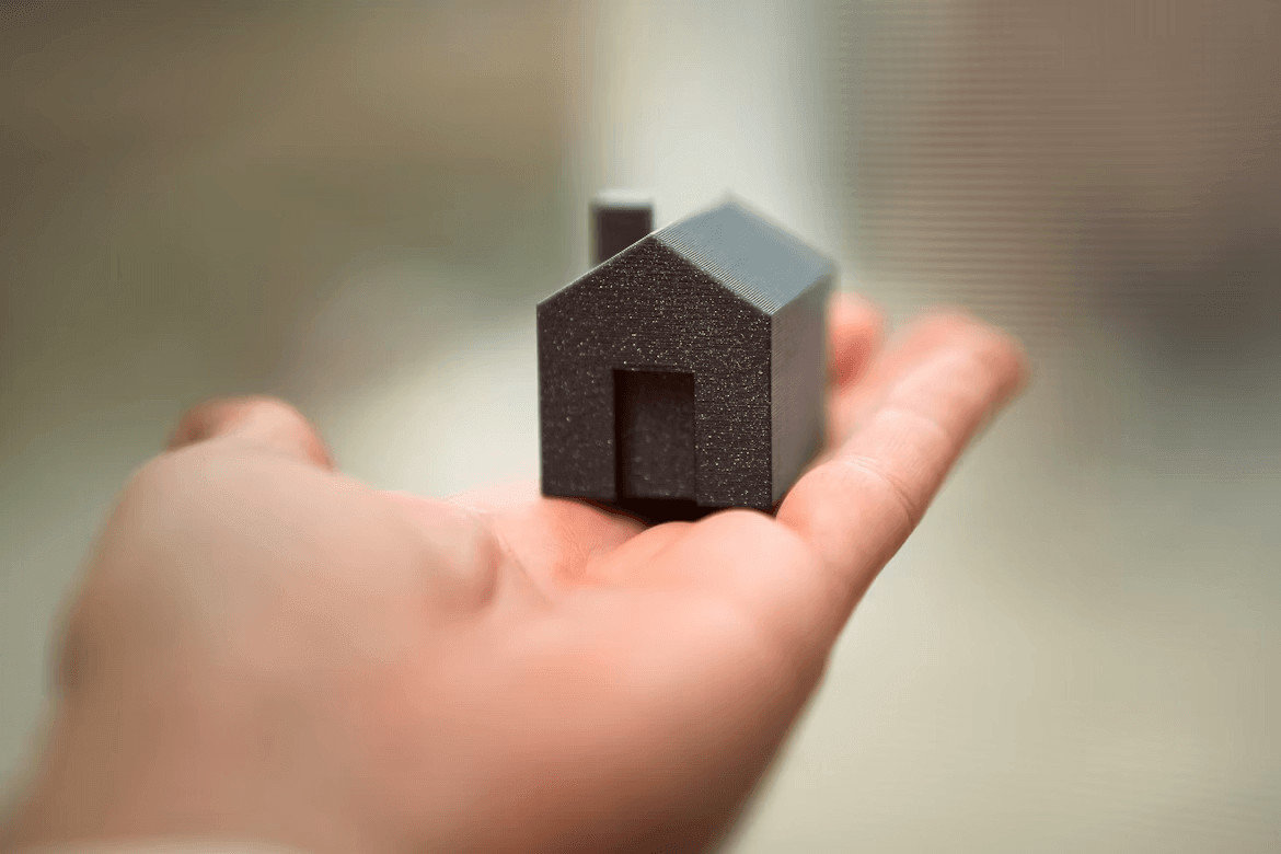 Hand holding a small house, symbolizing