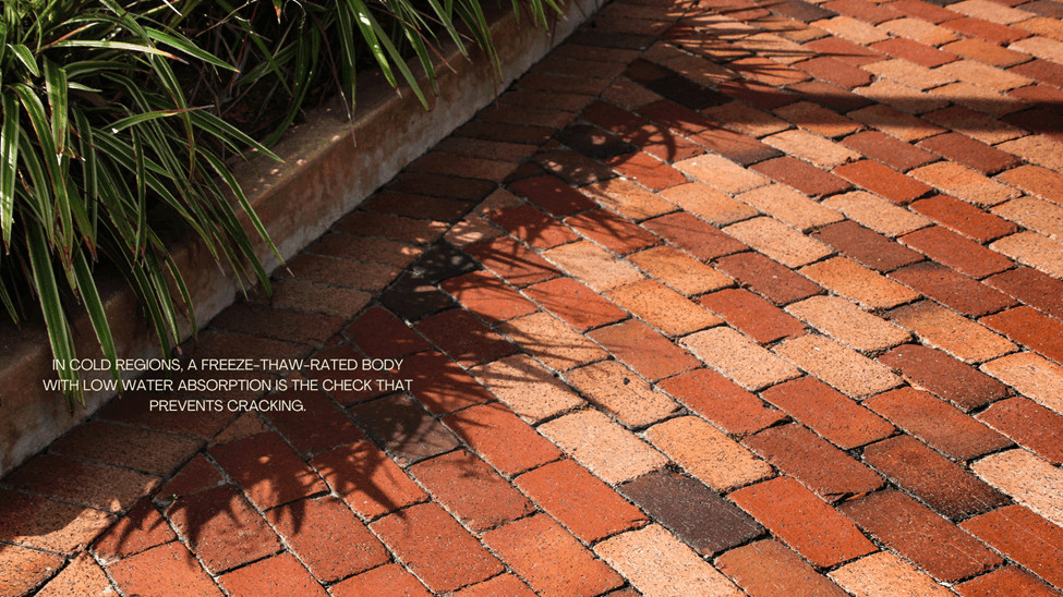 Outdoor red brick paving with grass growing between the