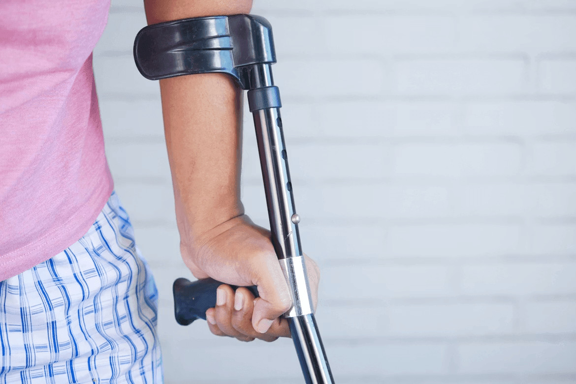 Person holding a crutch and walking cane after