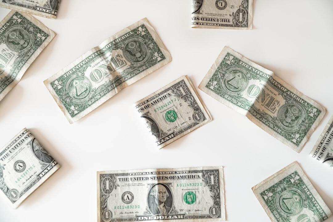 Several US one-dollar bills scattered across a plain white background