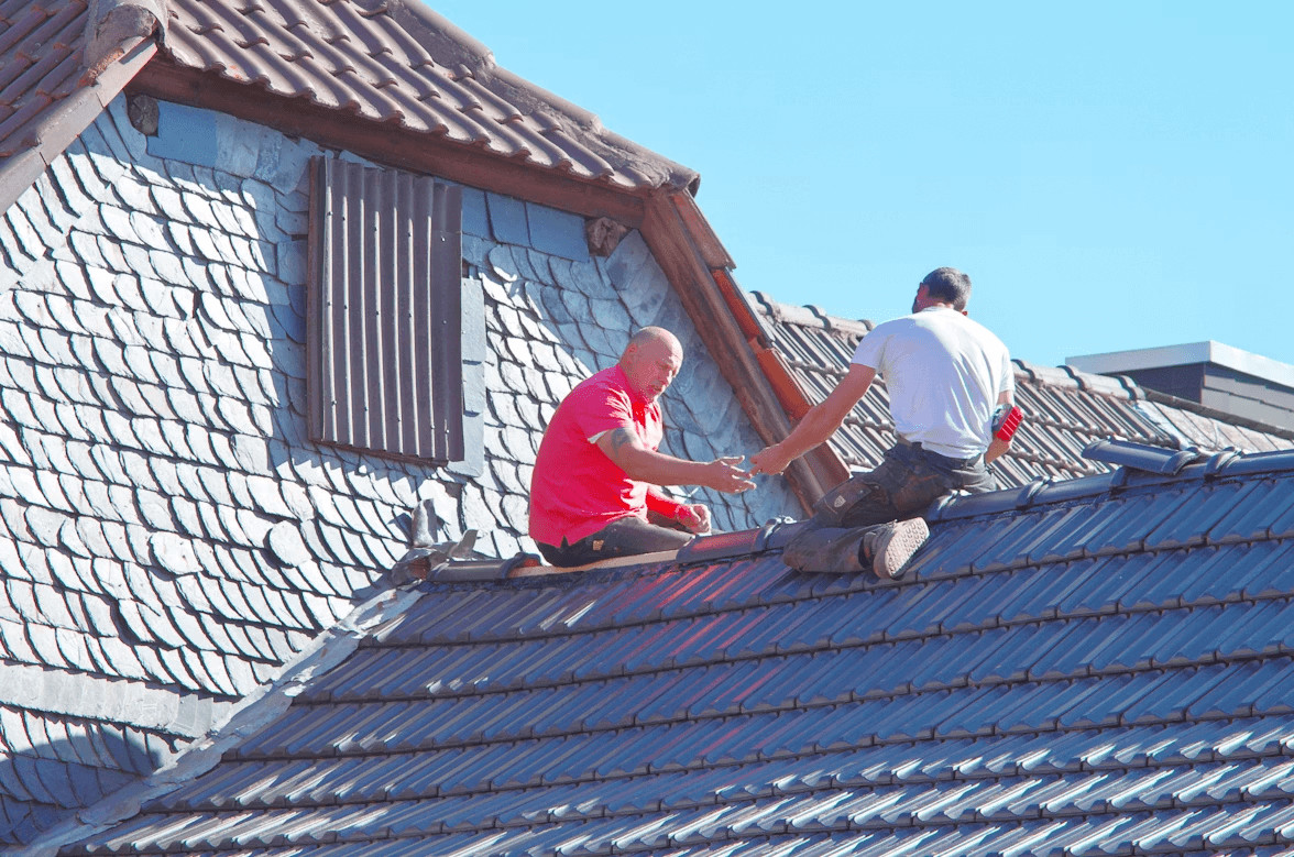 Choosing the Right Roofing Material for Your Climate and Budget 1 Two men installing roofing material on a house roof
