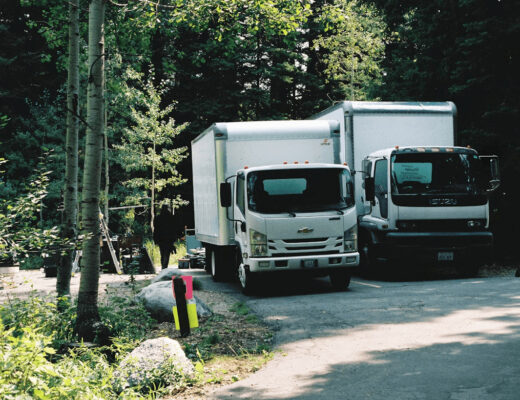Two moving trucks parked outside a historic Piedmont home