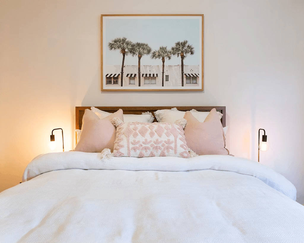A bed with a white comforter and pink pillows
