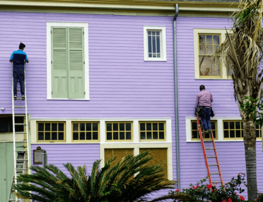 Two men painting the exterior of a purple house