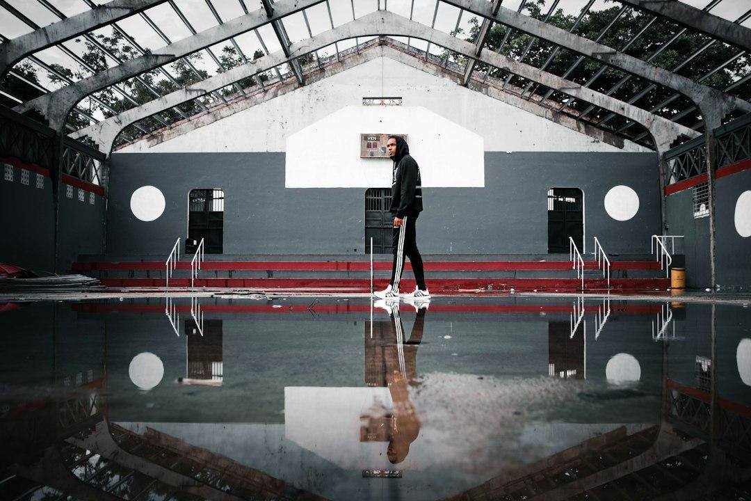 A person operating a walk-behind floor scrubber in a large room