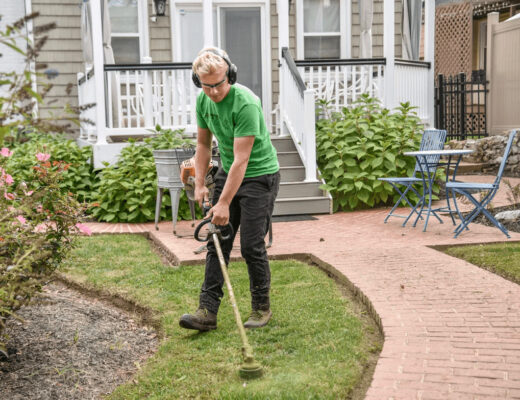 Man mowing lawn as part of a yard maintenance plan