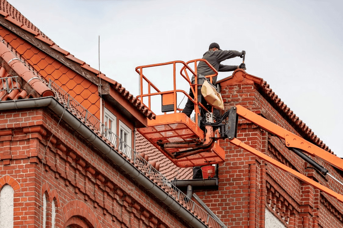 Man installing energy-efficient roofing on a red brick