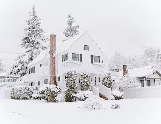 Beyond Flashlights and Batteries: Preparing Your Home for Winter Storms 1 White house covered in snow, ready for