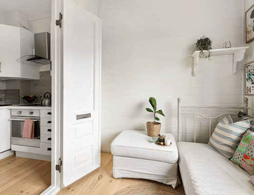 White kitchen with couch and plant in small apartment